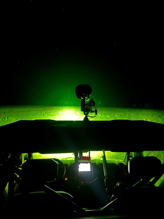 All-terrain vehicle (ATV) with green hunting spotlight mounted on roof, used for night feral pest control and spotlighting